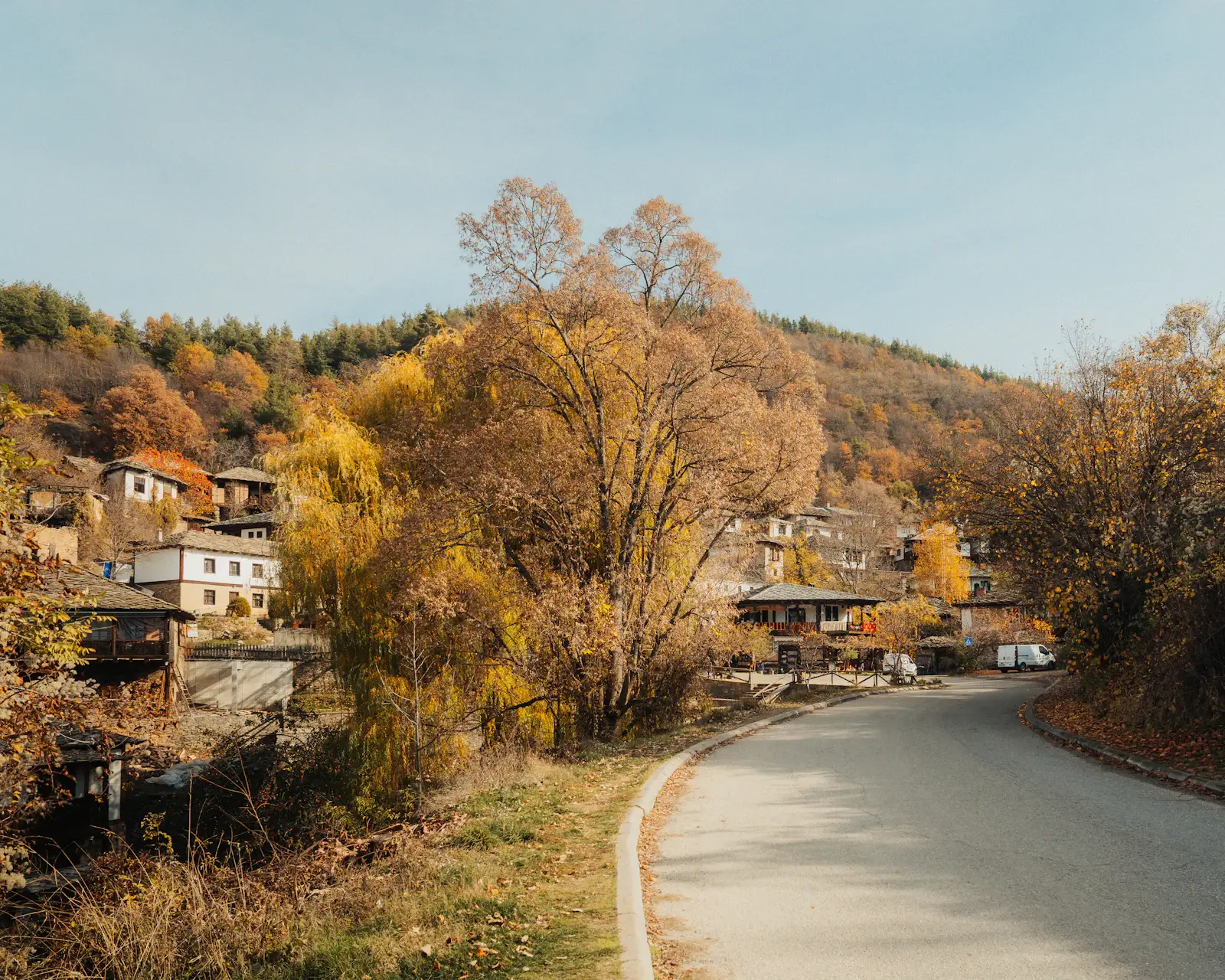 A winding village road through traditional houses and hills in Leshten, Bulgaria
